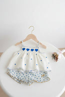 Children's dress with blue heart details on a white surface, Obroi