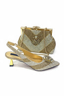 A gold rhinestone-embellished slingback high-heel shoe with a matching gold rhinestone clutch bag, displayed on a clean white background, Obroi