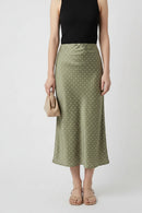 Person wearing a green polka dot skirt and black top on a white background, Obroi