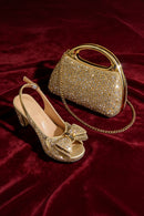 Gold high-heeled shoe and matching handbag with diamond-like stones on a red velvet background, Obroi