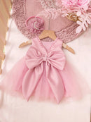 Pink dress with a large bow on a hanger against a soft pink background with flowers, Obroi