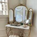 Vintage-style vanity table with marble top and gold-framed mirrors in a room, Obroi