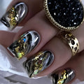 Close-up of a hand with metallic nail art and gold rings, Obroi