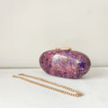 Pink and purple speckled clutch bag with gold chain on a white surface, Obroi