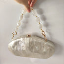 Handbag with shell design and beaded handle on a light background, Obroi