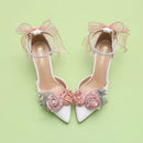 White high-heeled shoes with pink floral decorations on a light green background, Obroi