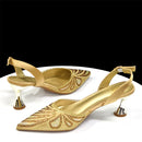 Gold high-heeled shoes with intricate designs on a white surface, Obroi