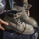 Close-up of a person holding a pair of brown leather boots with black laces, Obroi