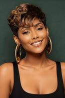Woman with styled hair and gold hoop earrings against a green background, Obroi