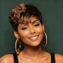 Woman with styled hair and gold hoop earrings against a green background, Obroi