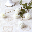 White flowers and green leaves on a textured white surface with lace patterns, Obroi