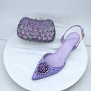 Purple stiletto shoes and matching clutch on a white plate, Obroi