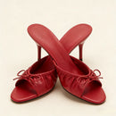 Red high-heeled shoes with bow details on a beige background, Obroi