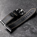 Obroi Black leather watch strap with gold stitching on a dark surface