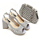 A matching silver rhinestone-embellished women's outfit set featuring a pair of open-toe high-heeled pumps and a structured clutch handbag, displayed on a clean white background, Obroi