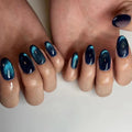 Close-up of hands with blue and black glittery nail polish on a neutral background, Obroi