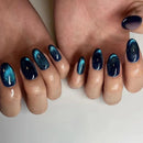 Close-up of hands with blue and black glittery nail polish on a neutral background, Obroi