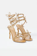 Beige high-heeled sandals with gold embellishments on a light gray background, Obroi