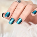Hand with teal glittery nail polish on a neutral background, Obroi
