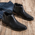 Black leather boots on a wooden floor with jeans in the background ,Obroi