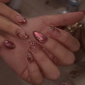 Close-up of a hand with decorative nail art featuring flowers and gold accents, Obroi