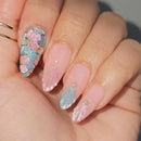 Close-up of a hand with pink and blue glittery nail design, Obroi