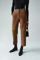 Person wearing brown pants and black top on a white background, Obroi