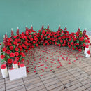 Decorative arch made of red roses with candles on a wooden floor, featuring the brand 'Obroi'.