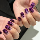 Close-up of hands with purple nail polish featuring a leopard print design, Obroi