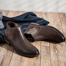 Pair of brown leather boots on a wooden floor with jeans in the background ,Obroi
