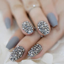 Nails with gray polish and decorative studs on a neutral background, Obroi