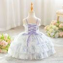 A toddler girl's ball gown dress displayed on a dress form mannequin. The dress features a white base with a light purple floral pattern, a lace-up corset-style bodice with purple straps, and a tiered ruffled skirt, Obroi