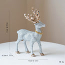 Decorative deer figurine with glittery silver body and gold antlers on a beige , Obroi