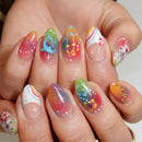 A close-up of a hand showcasing manicured almond-shaped nails with a variety of colorful nail art designs, including floral patterns, rainbow gradients, and small gold star accents, Obroi