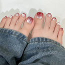 Close-up of feet with red and silver glitter nail polish, wearing blue jeans, Obroi