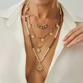 Necklace with sun pendant and layered gold necklaces on a white background, Obroi
