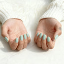 Close-up of hands with light blue nail polish on a white background, Obroi