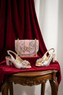 Decorative shoes and handbag with embellishments on a red fabric background, Obroi