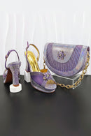 Purple high-heeled shoes with gold accents and a matching handbag on a black surface, Obroi