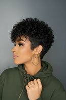 Woman with short, curly black hair wearing a green hoodie against a gray background, Obroi