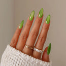 Hand with green nail polish wearing a ring on a neutral background, Obroi