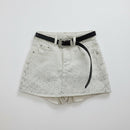 White distressed denim shorts with a black belt featuring a silver rhinestone buckle, laid flat on a light gray background, Obroi