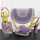 Purple high-heeled shoes with gold accents and a matching purple handbag on a black surface, Obroi