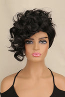 A short, voluminous black curly wig displayed on a mannequin head against a plain beige background, Obroi