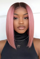 A woman wearing a straight, shoulder-length wig with a dark brown root and pink tips, styled with a center part, Obroi
