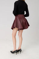 Person wearing a black sweater and maroon pleated skirt on a white background, Obroi