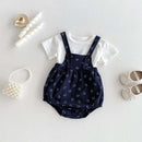 Navy blue romper with white pattern and white shirt underneath, on a light gray background.