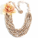 Multistrand beaded necklace with a large floral pendant on a white background, Obroi