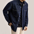Person wearing a dark blue denim jacket on a plain background, Obroi
