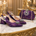 A pair of sparkling purple slingback heels with jeweled embellishments and a matching purple quilted handbag with a chain strap, displayed on a marble and gold console table in an ornate room, Obroi